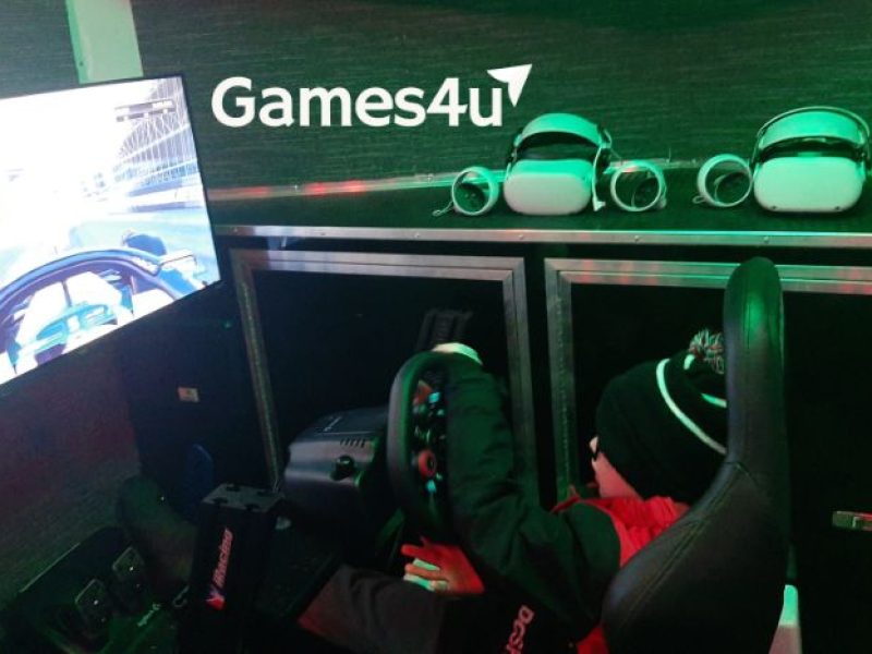 Boy playing racing simulator inside Games4u video game truck